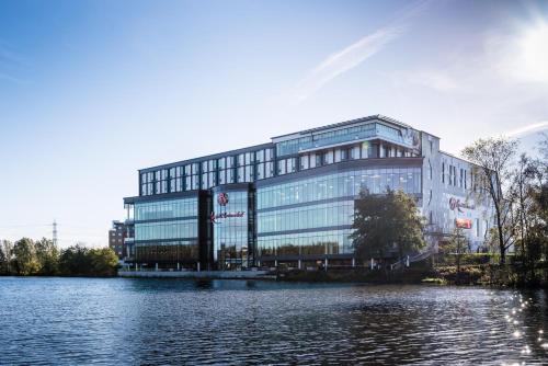 a large glass building next to a body of water at Genting Hotel & Spa at Resorts World Birmingham in Bickenhill