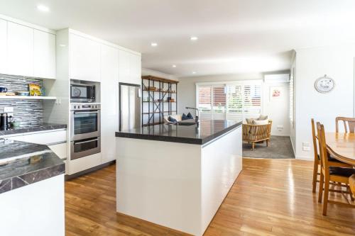 a kitchen with white cabinets and a dining room at Spacious Coastal Retreat, Ideal for Families in Mangawhai