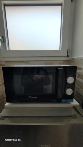 a microwave sitting under a window with a tv on top at Ammiria in Cetara
