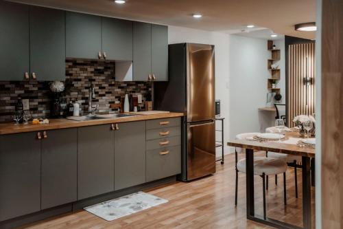 a kitchen with gray cabinets and a table and a refrigerator at The Barrie Nook in Barrie