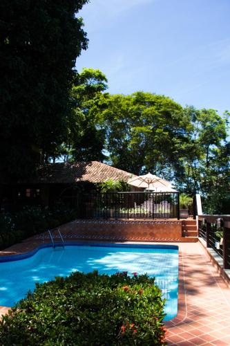 a swimming pool with a fence and an umbrella at Pousada da Mata in Iriri