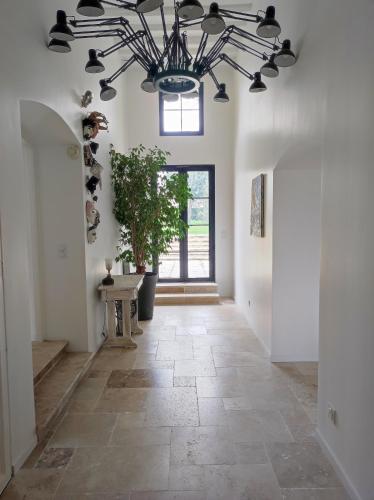 un couloir avec un grand lustre et du carrelage dans l'établissement Spacieuse Villa à 5 min à pieds du centre ville d'Uzès, à Uzès