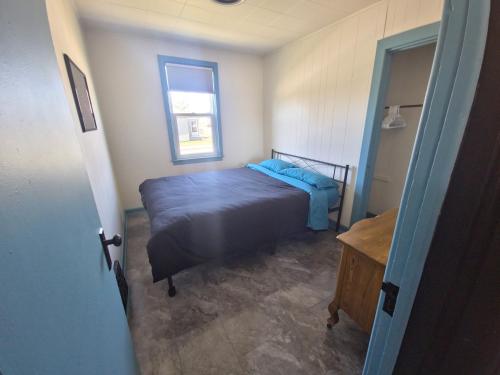 a bedroom with a bed with a blue comforter and a window at Minutes to Downtown & Ideal for Long-term Stays in Kingston