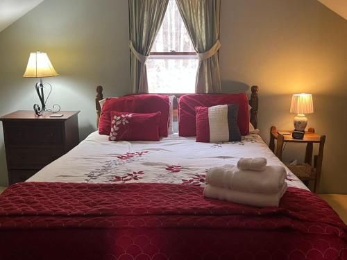 1 dormitorio con 1 cama grande con sábanas y almohadas rojas en Cozy Catskill Mountain Cabin, en Margaretville