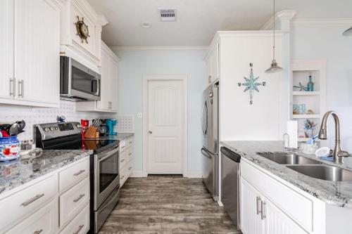 a kitchen with white cabinets and a sink at Gulf View 3BR 2BA Steps to Beach 2 King Beds in Bolivar Peninsula