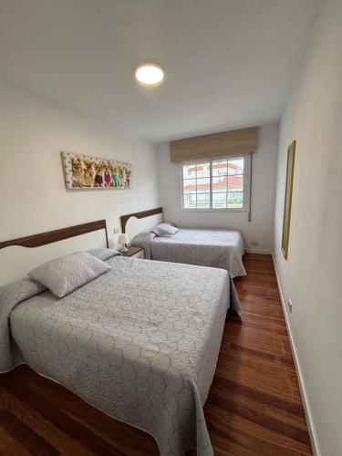 a bedroom with two beds and a window at Enjoy Sanxenxo,200m Playa, Balcón Vistas Cíes, Piscina & Terraza Azotea,2 plazas Garaje, 2 Baños, Muy Luminoso, Muy Tranquilo,Muy Equipado, Céntrico in Sanxenxo