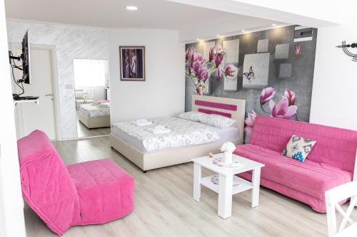 a living room with a pink couch and a bed at Apartmani HM in Trebinje