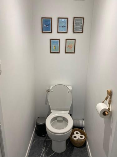 a bathroom with a toilet with four pictures on the wall at L'Echappée Bleue in Plougonvelin