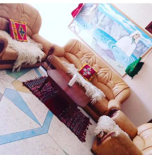 a living room with a couch with pillows on it at Maison d'hôtes Moussem des fiançailles in Imilchil