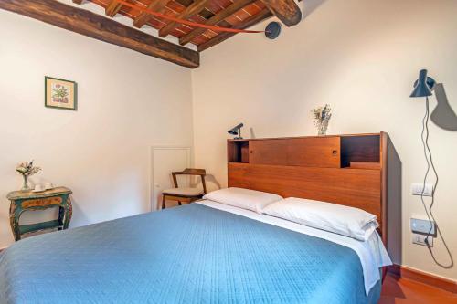 a bedroom with a blue bed with a wooden headboard at Pio Bove Rooms in Pietrasanta