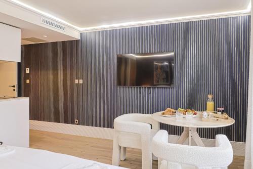 a dining room with a table and a tv on a wall at Divine Couture - Suite Vivienne in Carrières-sur-Seine