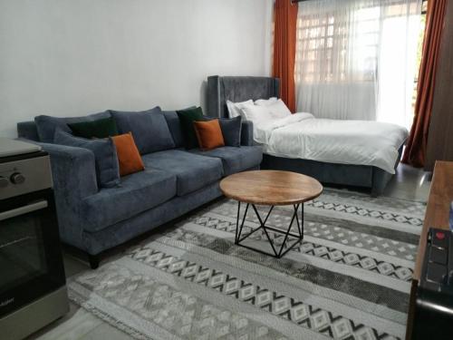 内罗毕Cozy Studio bnb in Kasarani Seasons, Nairobi的客厅里有一张蓝色的沙发和一张桌子