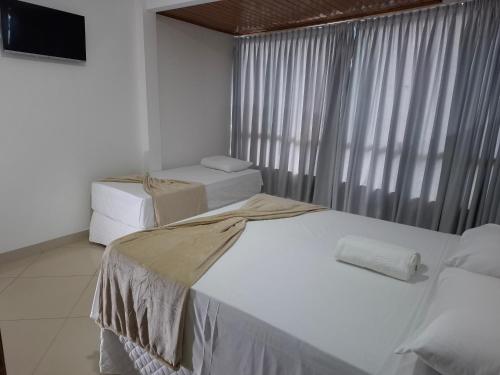a bedroom with two beds and a large window at Brisas do Mar HOTEL & APART in Valença