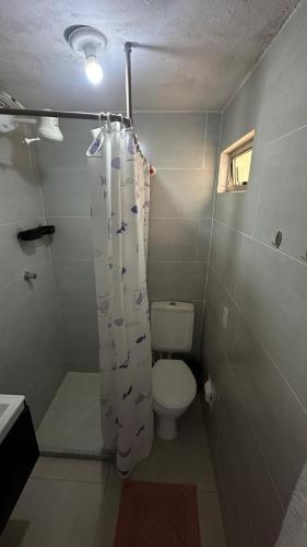 a bathroom with a toilet and a shower curtain at Hospedagem do Iago in Cabo Frio