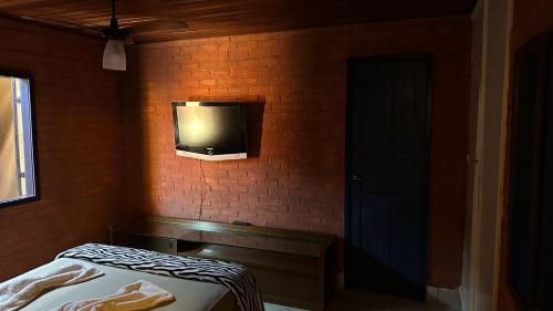 a bedroom with a tv on a brick wall at Hospedagem do Iago in Cabo Frio