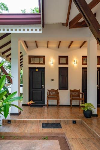 a front porch of a house with two chairs at The Villa By CMB Apartments in Negombo