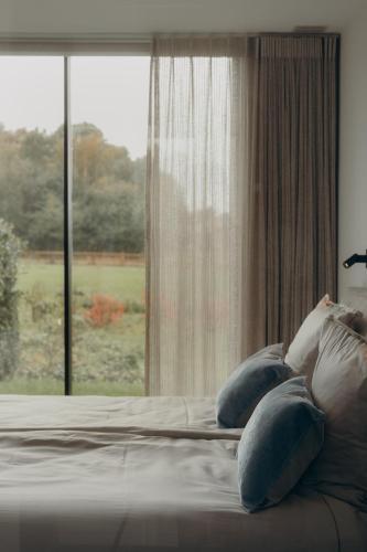 a bed with pillows in front of a window at Au Porte Bonheur in Zwalm