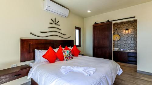 a bedroom with a large white bed with red pillows at Paz del Mar Room 05 Guacamaya Roja in Las Conchas