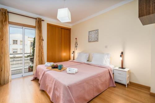 una camera da letto con un grande letto con una coperta rosa di Bright & Spacious Flat by HostWise a Vila Real de Santo António