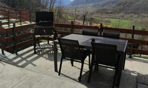 a table and chairs on a patio with a grill at Le Rive nel bosco in Capo di Ponte