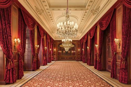 an empty hallway with red curtains and a chandelier at InterContinental Paris Le Grand by IHG in Paris