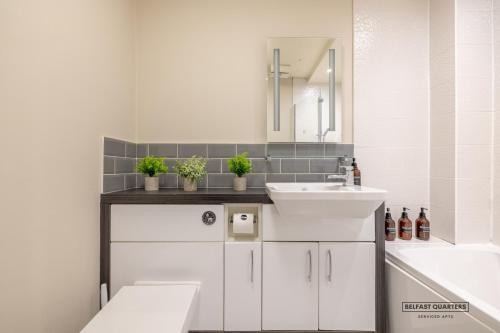 a white bathroom with a sink and a bath tub at Belfast Quarters Riverside in Belfast