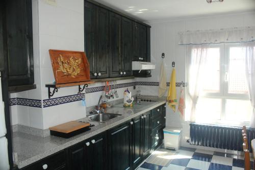 a kitchen with black cabinets and a sink and a window at Casa Luis in Riaño