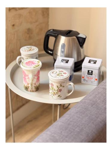 three coffee cups on a shelf with a tea kettle at Logis 2 Caen in Caen