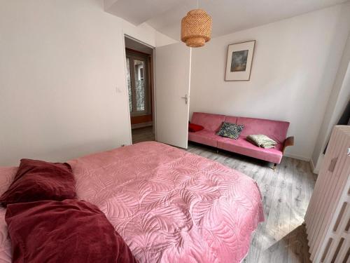 a bedroom with a pink bed and a couch at Logis 2 Caen in Caen