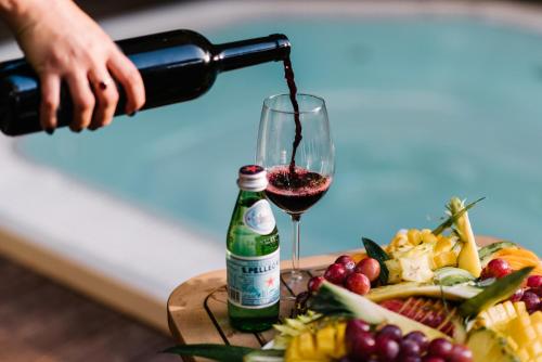 a person pouring wine into a glass next to a plate of food at Hagoshrim Hotel & Nature in Hagoshrim