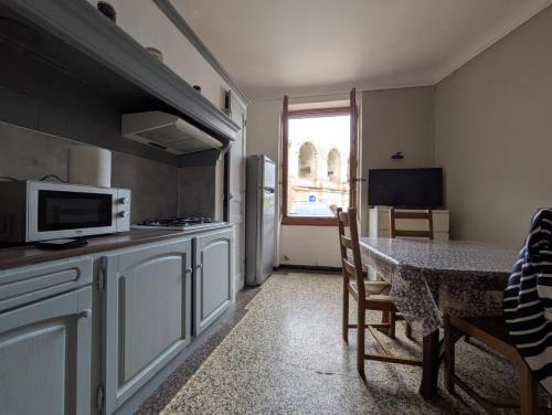une petite cuisine avec une table et un micro-ondes dans l'établissement Les nuitees arlesiennes, à Arles