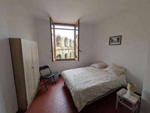 une chambre avec un lit, une fenêtre et une chaise dans l'établissement Les nuitees arlesiennes, à Arles