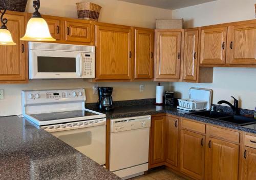 a kitchen with wooden cabinets and a white stove top oven at Bull Frog Bay #2 - Downtown Minocqua in Minocqua