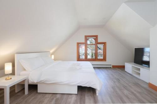 a white bedroom with a bed and a television at Cozy Heritage Home Near Main St in Vancouver
