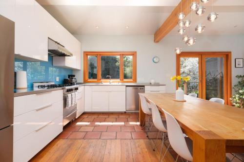 a kitchen with white cabinets and a wooden table at Cozy Heritage Home Near Main St in Vancouver