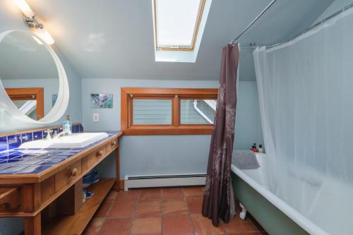 ein Badezimmer mit Badewanne, Waschbecken und Spiegel in der Unterkunft Cozy Heritage Home Near Main St in Vancouver