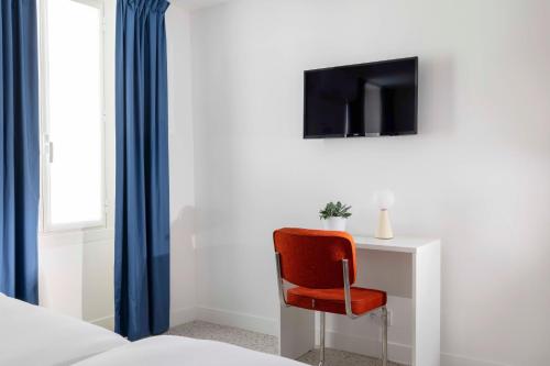 a red chair sitting next to a desk with a tv at Seb & Co in Paris
