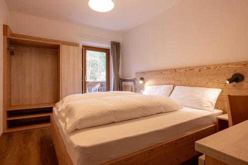 a bedroom with a large bed with a wooden headboard at SAN PIETRO DOLOMITI Small Budget Hotel in Ortisei