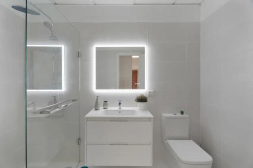 a white bathroom with a toilet and a sink at Apartamento Bonjour in Tenerife