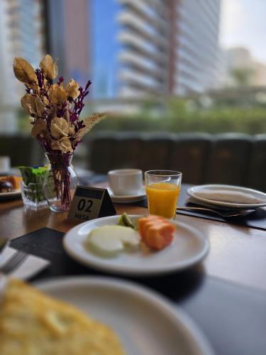 サン・カエタノ・ド・スルにあるQuality Hotel São Caetanoの食べ物の皿とオレンジジュースのグラスが置かれたテーブル