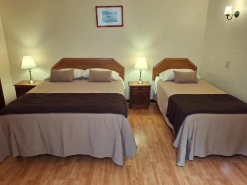 two beds in a hotel room with two lamps at Hotel Escorial in La Serena