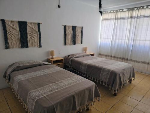 a bedroom with two beds and two windows at EL LIMÓN departamento in Oaxaca City