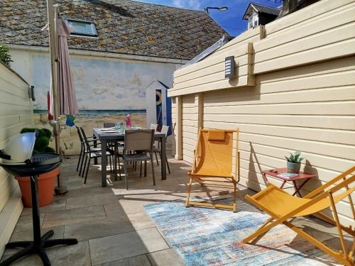 un patio avec une table et des chaises à côté d'un bâtiment dans l'établissement La plage en toile de fond!, à Trouville-sur-Mer
