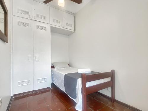 a small room with a bed and white cabinets at 4 Bedrooms AC Pitangueiras Sea View in Guarujá