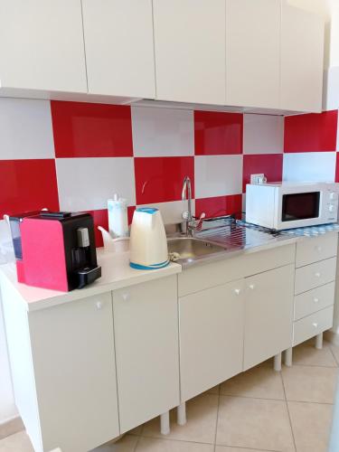 a kitchen with white cabinets and red and white checkered wall at TAnoelvira in San Lorenzo