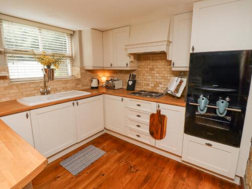 a kitchen with white cabinets and a black refrigerator at Edendale in Longframlington