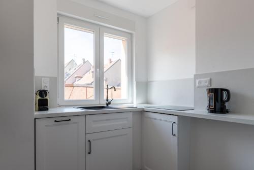 une cuisine blanche avec un évier et une fenêtre dans l'établissement Le Parisien d'Alsace, à Colmar