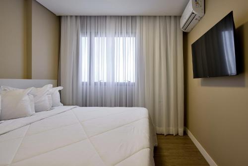 a bedroom with a large white bed and a window at Palazzo Torquetti in Belo Horizonte