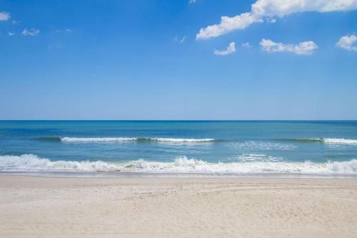 a sandy beach with waves in the ocean at Dolphin Run by Carolina Beach Realty in Kure Beach