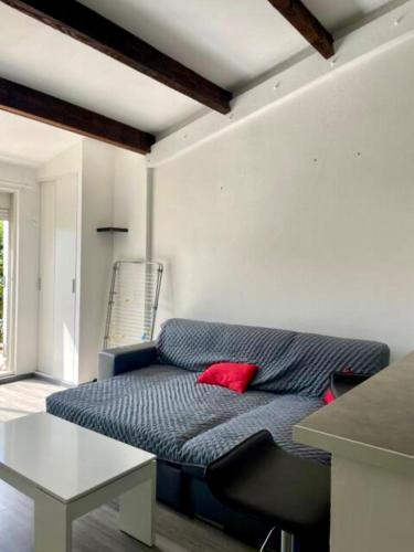 - un salon avec un canapé bleu et un oreiller rouge dans l'établissement Maison Paisible - 4pers - Histoire de clés, au Cap d'Agde